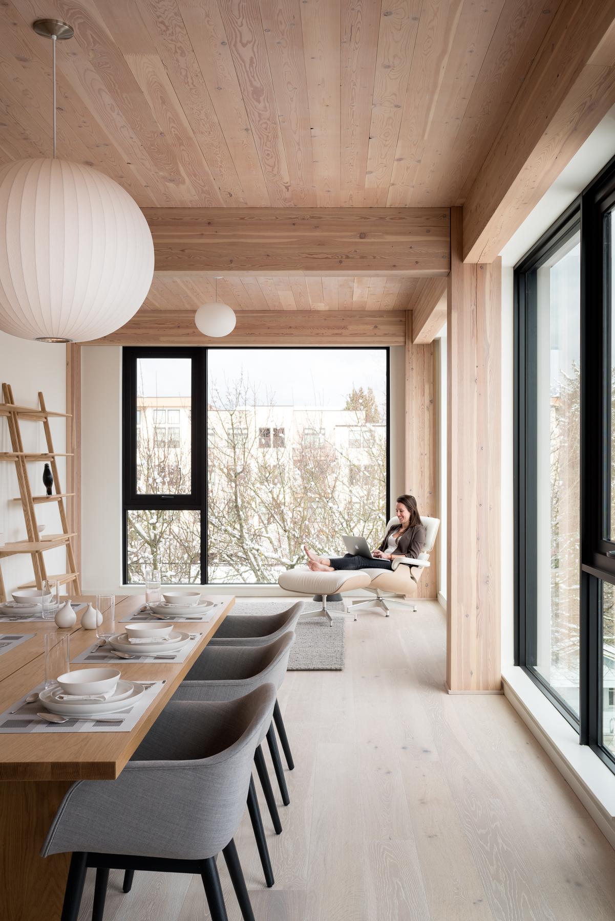 Carbon12 — sala con mujer en sofá y madera estructural vista